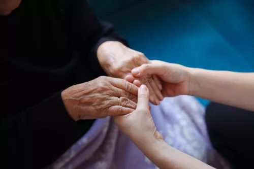 Young woman holding elderly hands